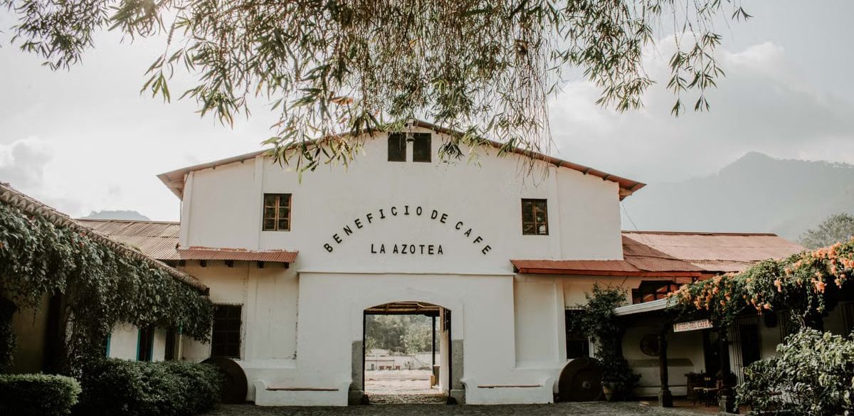 Charming historic building of Beneficio de Cafe La Azotea surrounded by lush greenery and cobblestones.